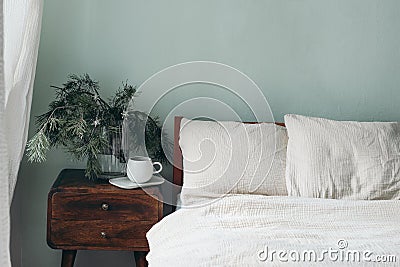 Christmas still life. Cup of coffee, retro wooden bedside table. Pine tree branches and silver stars ornaments in glass Stock Photo