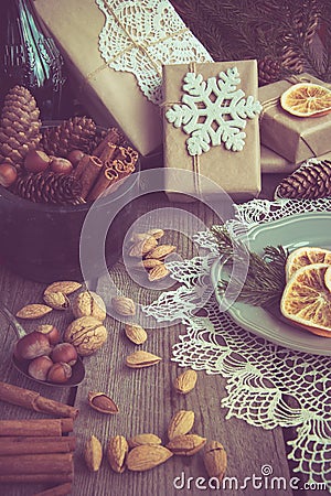 Christmas still life with giftbox, bowl with walnuts, almond, cinnamon, snowflakes on wooden table. Top view. Stock Photo