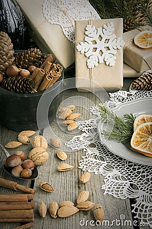 Christmas still life with present, almond, cinnamon, snowflakes on wooden table. Stock Photo