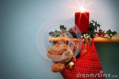 Christmas stocking with presents candle and holly. Stock Photo