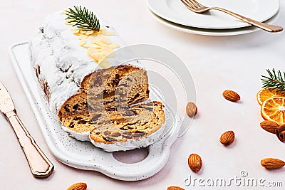 Christmas Stollen cake with icing sugar, marzipan, almonds and raisins on white serving plate Stock Photo