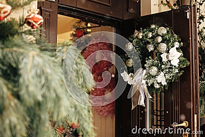 Christmas street decor. Stylish christmas wreath with silver ornaments on door at front store at holiday market in city street. Stock Photo