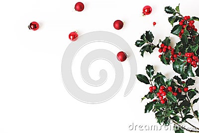 Christmas styled composition, decorative corner. Christmas glass balls, baubles and holly tree dark green leaves, red Stock Photo