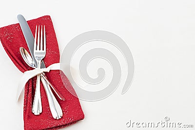 Christmas Table Place Setting with Silverware, Red Cloth Napkin on White Tablecloth Background with blank room or space for copy, Stock Photo