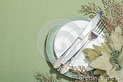 Christmas table setting with ceramic plates, traditional decor on Savannah Green color background Stock Photo