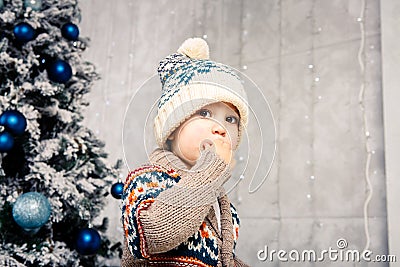 Christmas theme and children. Little Caucasian boy child in a warm hat and sweater posing, eating sweetness, dirty face. Christmas Stock Photo