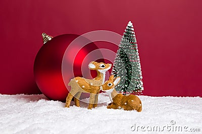 Christmas theme with miniature reindeers, Christmas tree and big bauble on red background Stock Photo