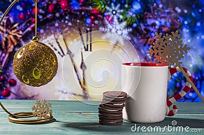 Christmas theme with toy ball, cookies and mug on green wooden surface against nice clock background Stock Photo