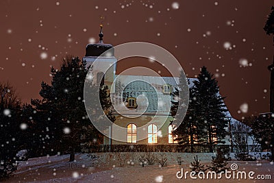 Christmas time, winter landscape, church in the evening in snowy weather, lit by lights Stock Photo