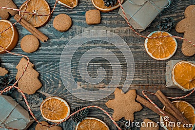 Christmas top view over a brown wooden background with gift boxes packed in a craft paper, cookies, dryed oranges, pine Stock Photo