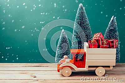 Christmas toy truck with gift boxes and pine tree on wooden table over green background Stock Photo