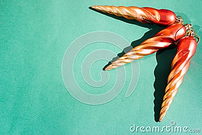 Christmas toys and decorations for Christmas tree. Three orange toy icicles on a light green background. Beautiful minimalistic Stock Photo
