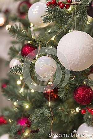 Christmas toys, red and white balls with lights on the Christmas tree, fir branches Stock Photo