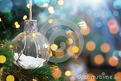 Christmas transparent bauble hanging on the brunch with bokeh and lights. Copy space Stock Photo