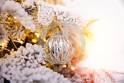 Christmas tree background with artificial snow decorated toys balls, branch golden illumination Stock Photo