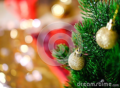 Christmas tree branch. Cozy . Two small cristmas-tree balls with golden glitter hang on needles of lush green. The background is Stock Photo