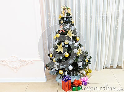 Christmas tree decorated with toys with gifts in boxes under it on a light background Stock Photo