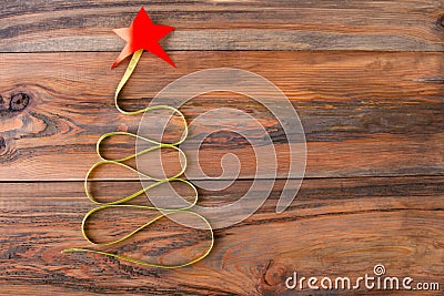 Christmas tree made of green ribbon with a red star on the wooden background. Stock Photo