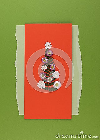 Christmas tree made from pressed dried flowers on a red postcard. Handmade Christmas greeting card in oshibana technique Stock Photo