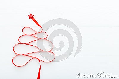 Christmas Tree made from Red satin ribbon with a star on the top on white wooden background. Xmas, winter, new year concept. Flat Stock Photo