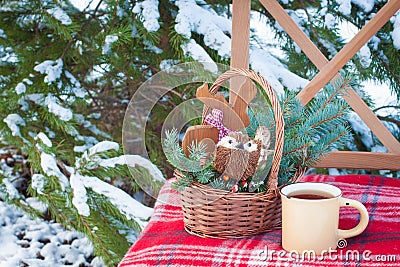 Christmas-tree toys in basket with cup of coffee on wool blanket on the chair near firewood Stock Photo