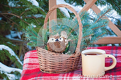 Christmas-tree toys in basket with cup of coffee on wool blanket on the chair near firewood Stock Photo