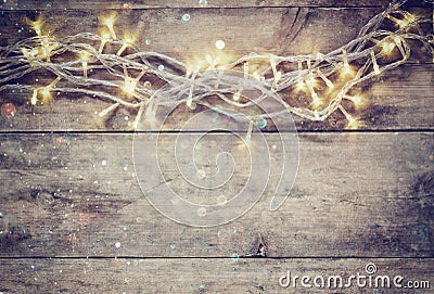 Christmas warm gold garland lights on wooden rustic background. filtered image with glitter overlay. Stock Photo