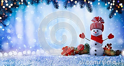 Christmas or winter background with with funny snowman, gift box and fir tree branches in wintery scenery. Fairy holiday card Stock Photo