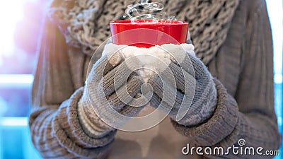 Christmas winter background - Young pretty woman with gloves and scarf stands on the balcony and holds a hot steaming teacup in Stock Photo