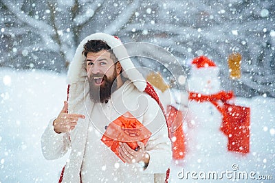 Christmas man in snow. Christmas winter people portrait. Man with red gift playing with snowman in winter park. Handsome Stock Photo