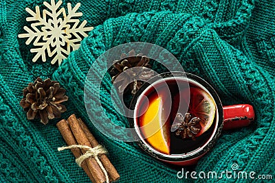 Christmas and winter traditional hot beverage. Mulled wine in red mug with spice wrapped in warm green sweater. Stock Photo