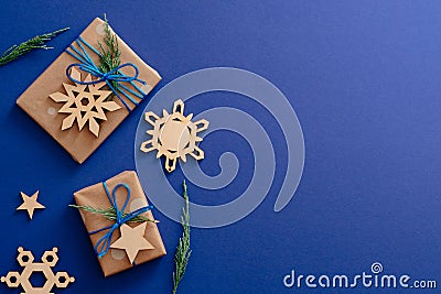 Christmas wooden decorations and gift boxes on dark blue background with copy space. Xmas card mockup, festive social media banner Stock Photo