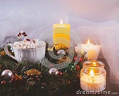 Christmas wreath, cup of marshmallows and lighted candles. Festive Christmas composition. Stock Photo