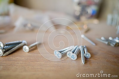 chrome-colored screws on a wooden table. close-up Stock Photo