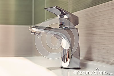 chrome faucet washbasin. Closed the tap dripping water in the bathroom. Waste of water. crane silver color with white sink in the Stock Photo