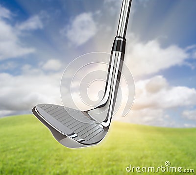 Chrome Golf Club Wedge Iron Against Grass and Blue Sky Background Stock Photo