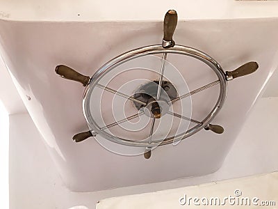 Chrome-plated rustproof metal shiny steering wheel with wooden handles in the captain`s cabin for control on the ship, boat, crui Stock Photo