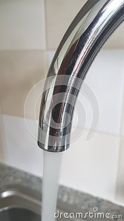 Chrome plated tap at home where water is coming out.. Stock Photo