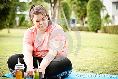 Chubby tried woman looking to glass of sweet drinks on natural garden in new normal condition after Corona epidemic.weight woman g Stock Photo