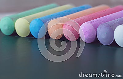 Chunks of multicolored chalk, pastels on the school board. Yellow, pink, red, green, gray, light green crimson. Close-up Stock Photo