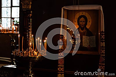 Church candles burn in a candlestick against the backdrop of icons Stock Photo