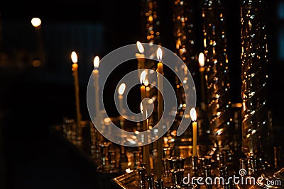 Church candles burn in a candlestick against the backdrop of icons Stock Photo