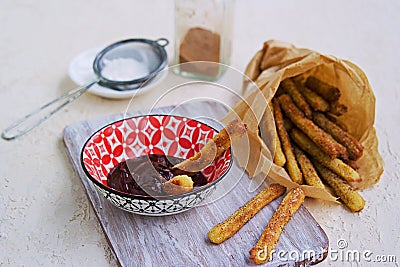 Churros, sweet fried fried choux pastry dough, sprinkled with sugar and ground cinnamon. Served with chocolate sauce. Stock Photo