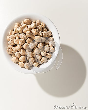 Chickpeas legume. Grains in a bowl. Shadow over white table. Stock Photo