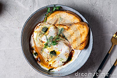 Cilbir or Turkish Eggs. poached eggs topped over herbed greek yogurt, drizzled with hot spiced paprika olive oil Stock Photo