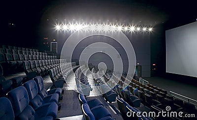 Cinema interior with lights on. Chairs and screen. Stock Photo
