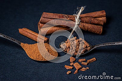 Cinnamon on a black background. A spoonful of young cinnamon lies next to a spoonful of crushed cinnamon. Stock Photo