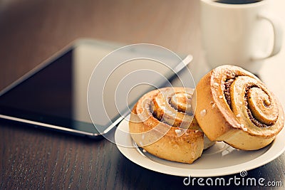 Cinnamon rolls, cup of coffee and computer tablet Stock Photo