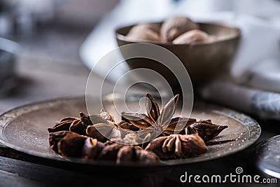 Cinnamon sticks, nutmeg and anise stars in cups over dark scorched wooden background Stock Photo