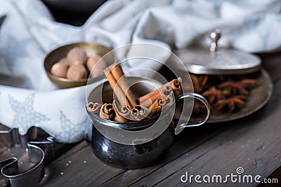 Cinnamon sticks, nutmeg and anise stars in cups over dark scorched wooden background Stock Photo